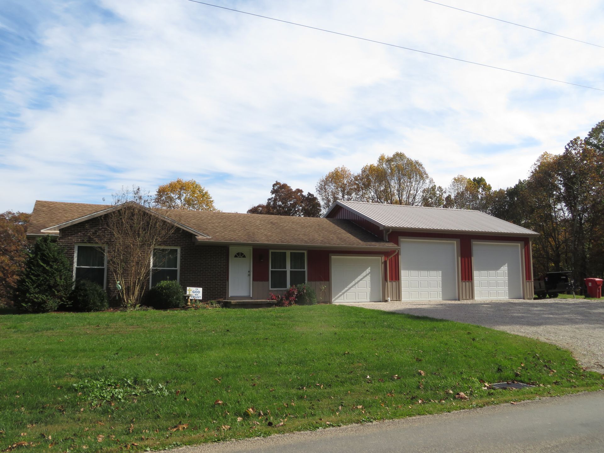 Single-story house with red trim and three-car garage behind a grassy front yard