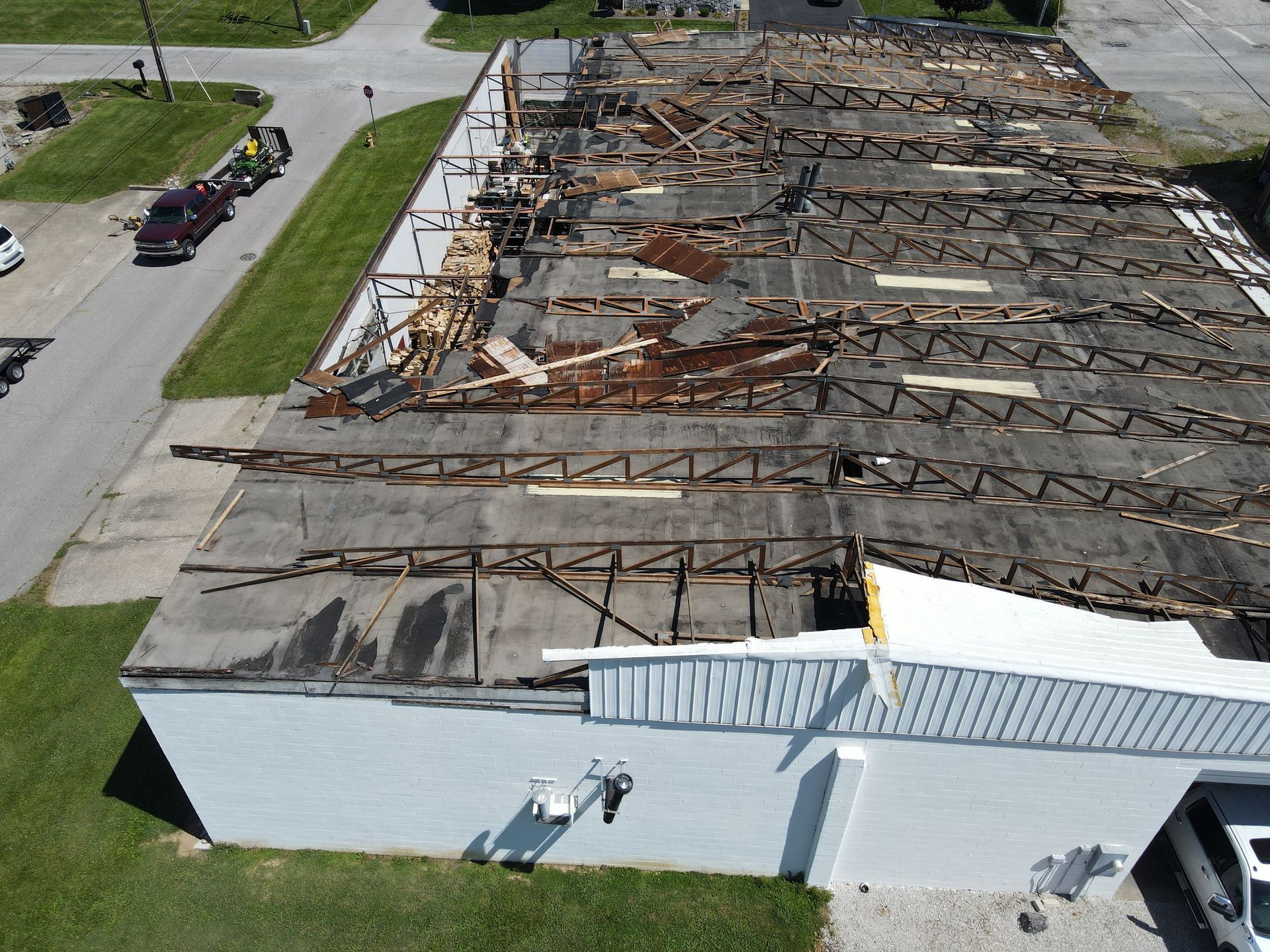 Damaged building with a severely collapsed roof and scattered debris viewed from above
