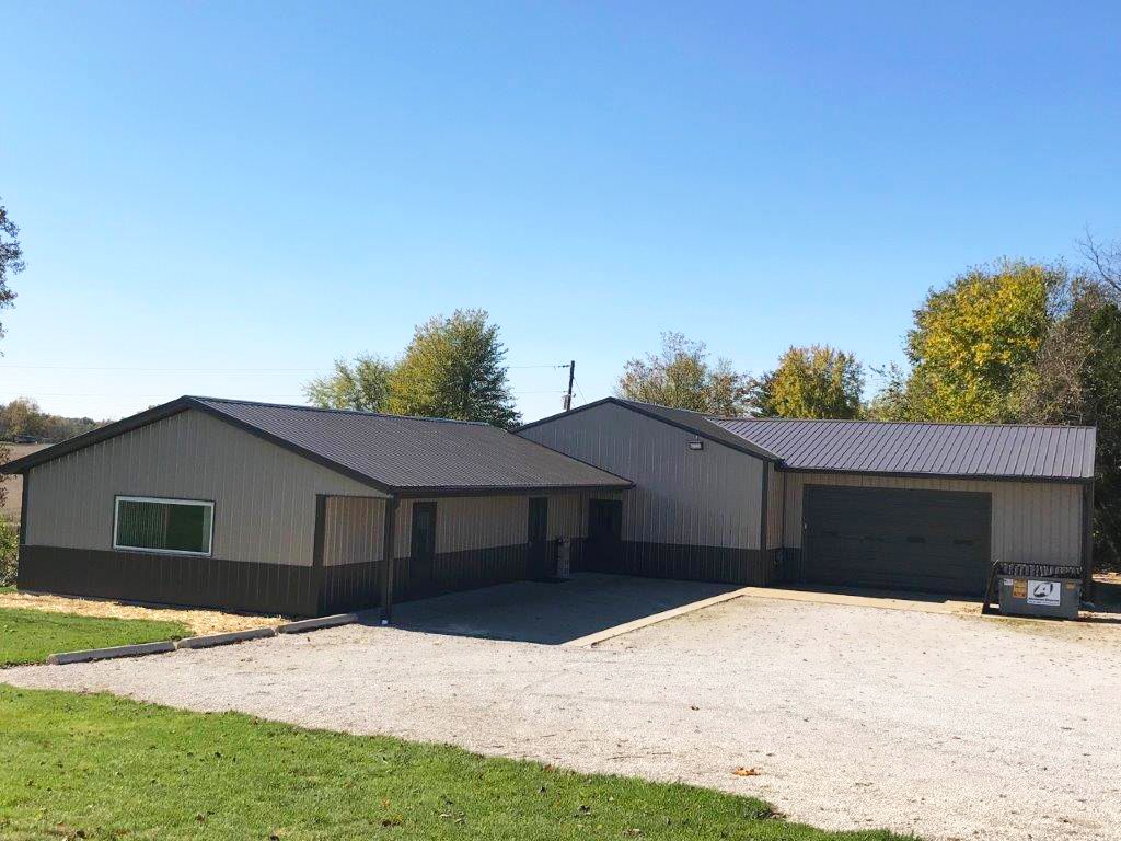 Single-story tan house with a large gravel driveway and attached garage under a blue sky