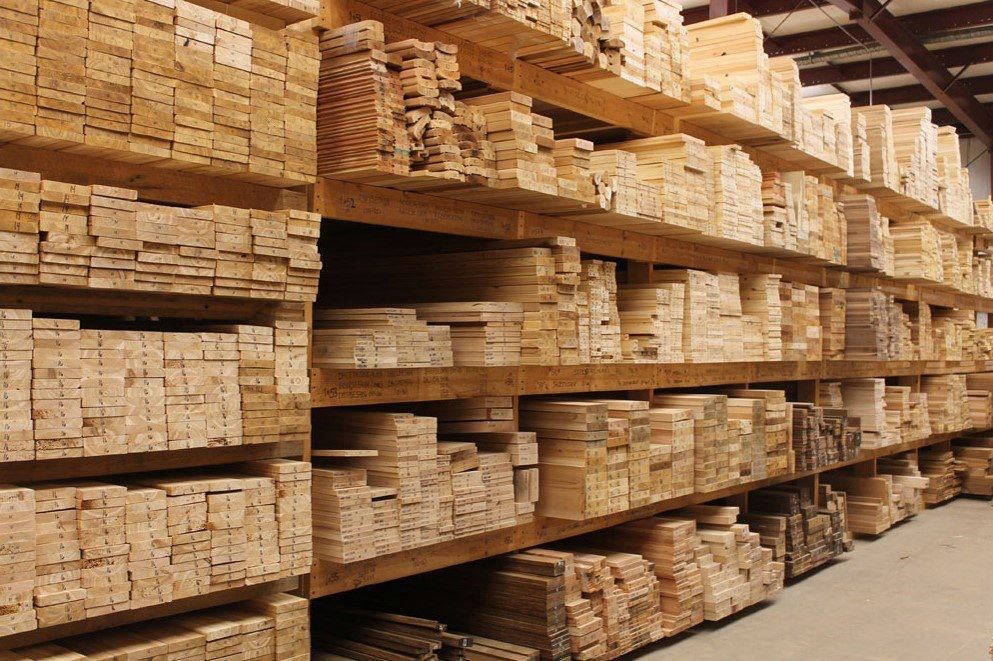 Stacks of cut lumber boards stored on warehouse shelves in a lumberyard