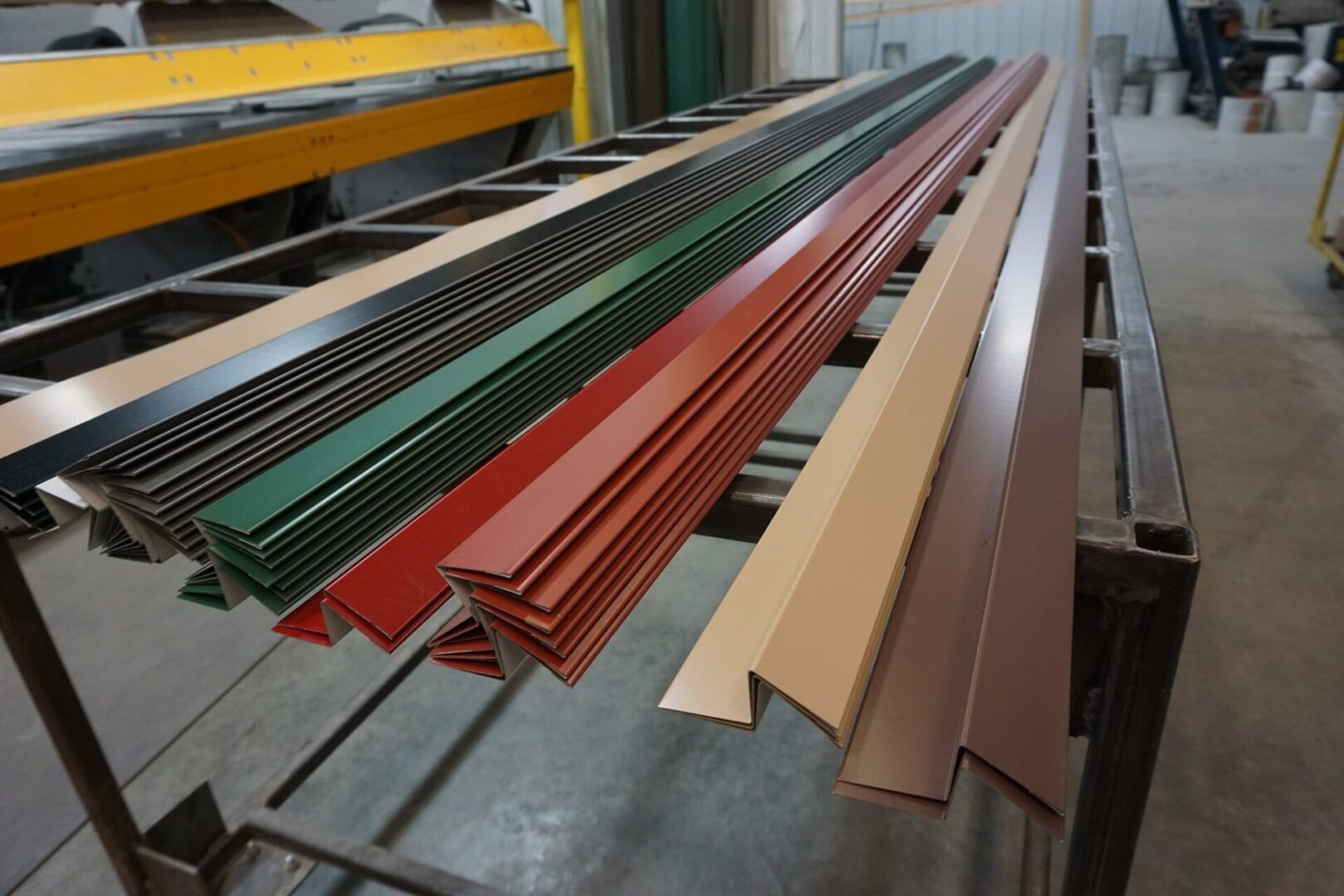 Bundles of colored metal roof panels stacked on a factory conveyor table