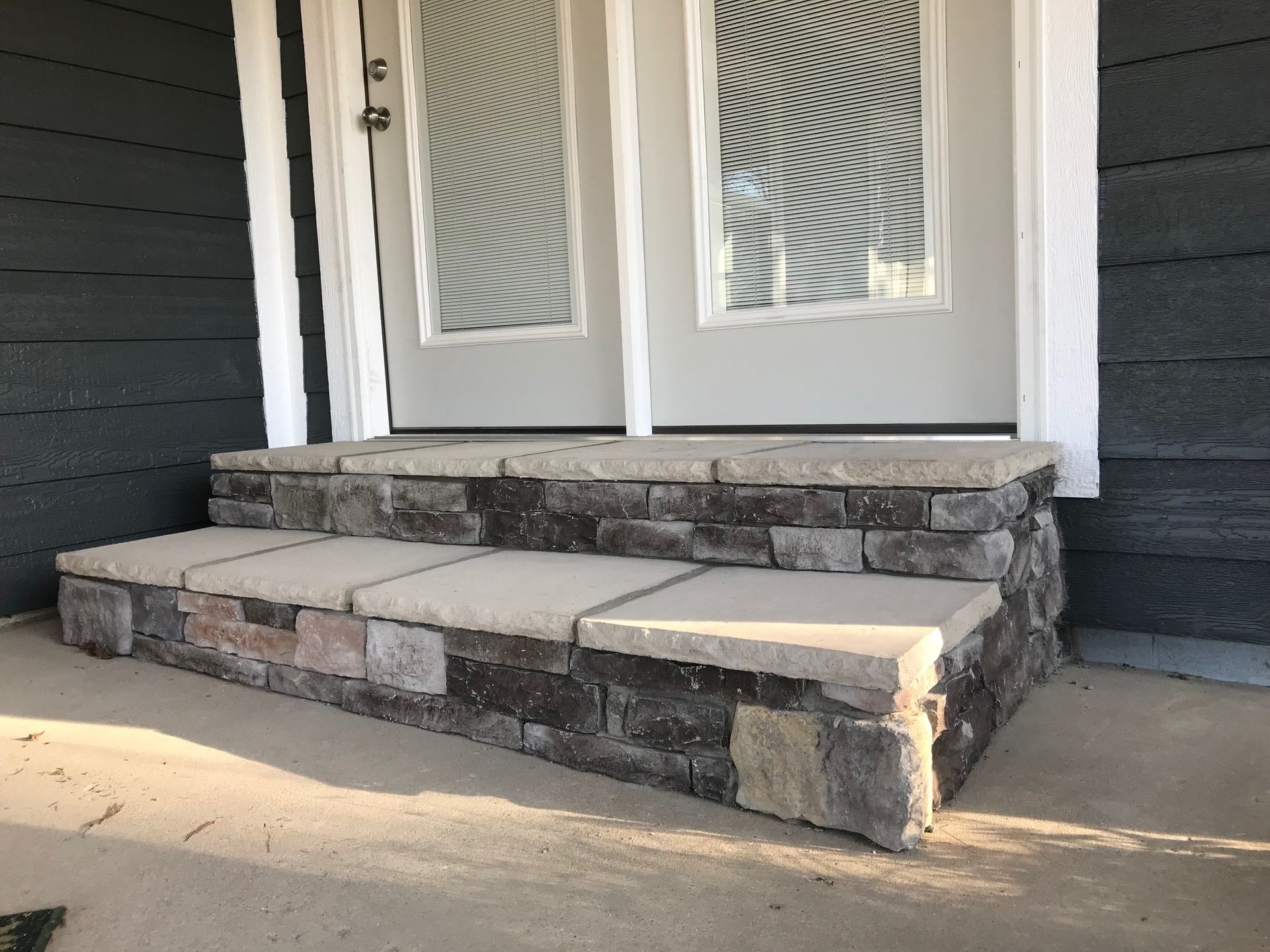 Front porch entrance with damaged concrete steps and double doors, showing a cracked left step.