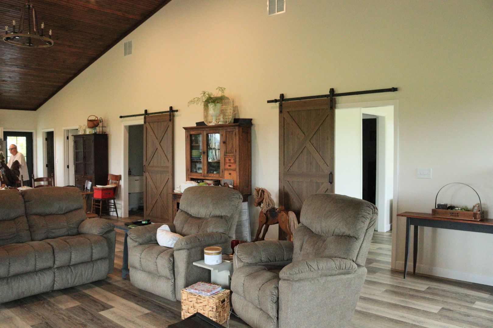 Rustic living room with leather recliners, sofa, wood cabinet, and barn doors on cream walls