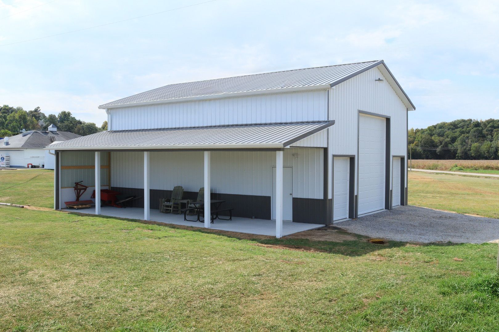 White metal barn with a covered porch on a grassy rural property