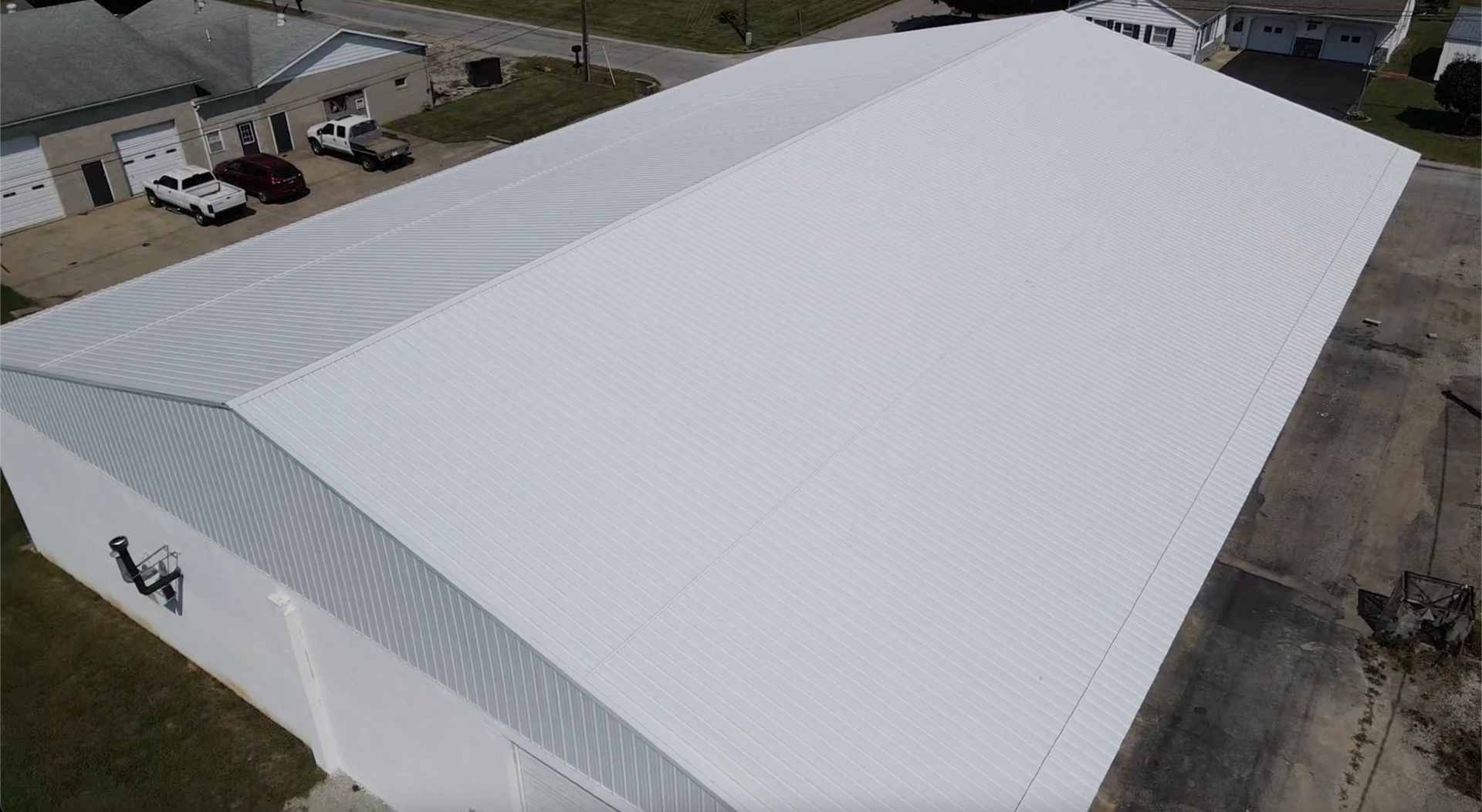 Aerial view of a large white-roofed industrial building in a paved lot.