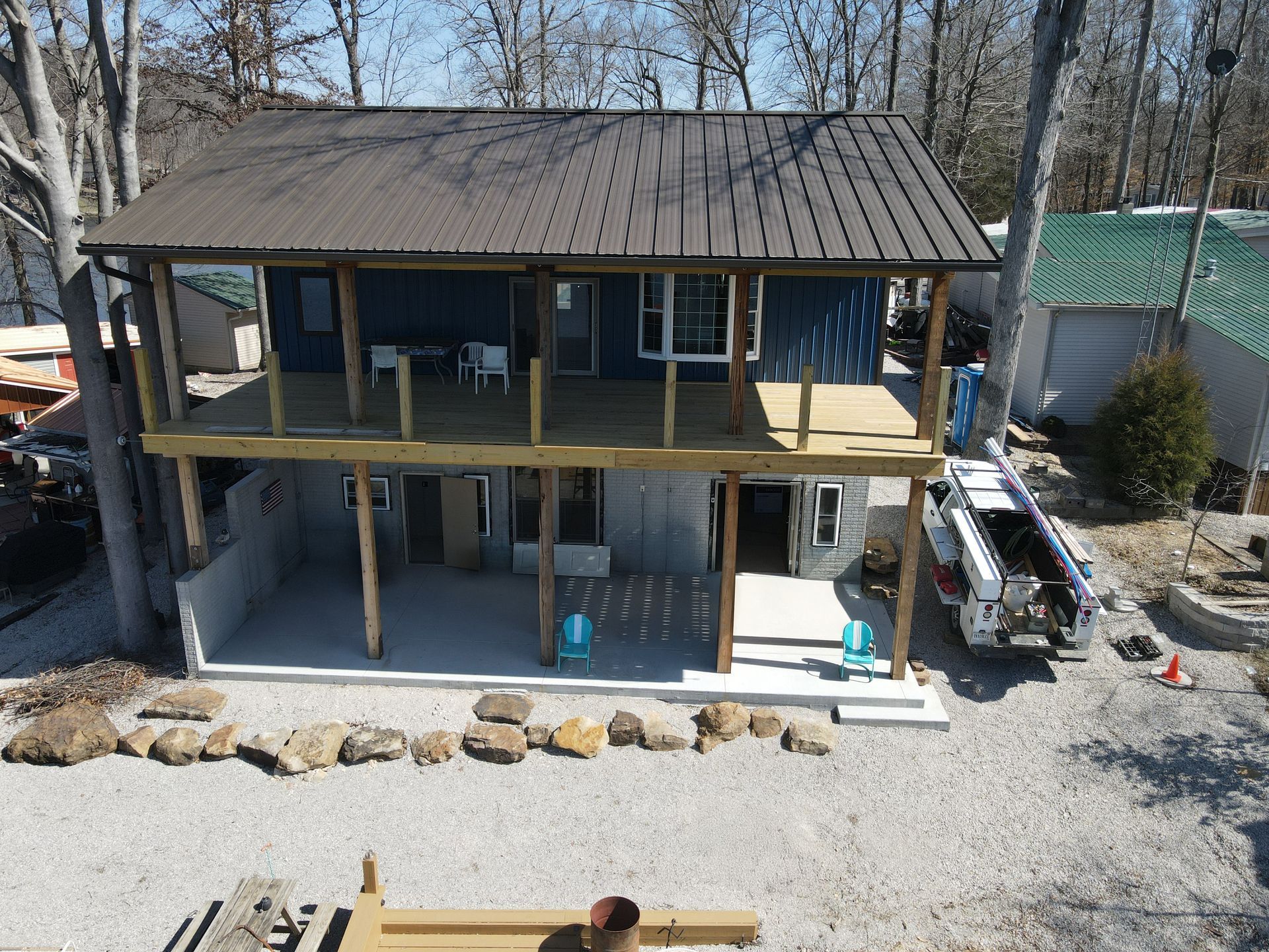 Two-story house with covered porches and gravel yard, viewed from the front in winter.