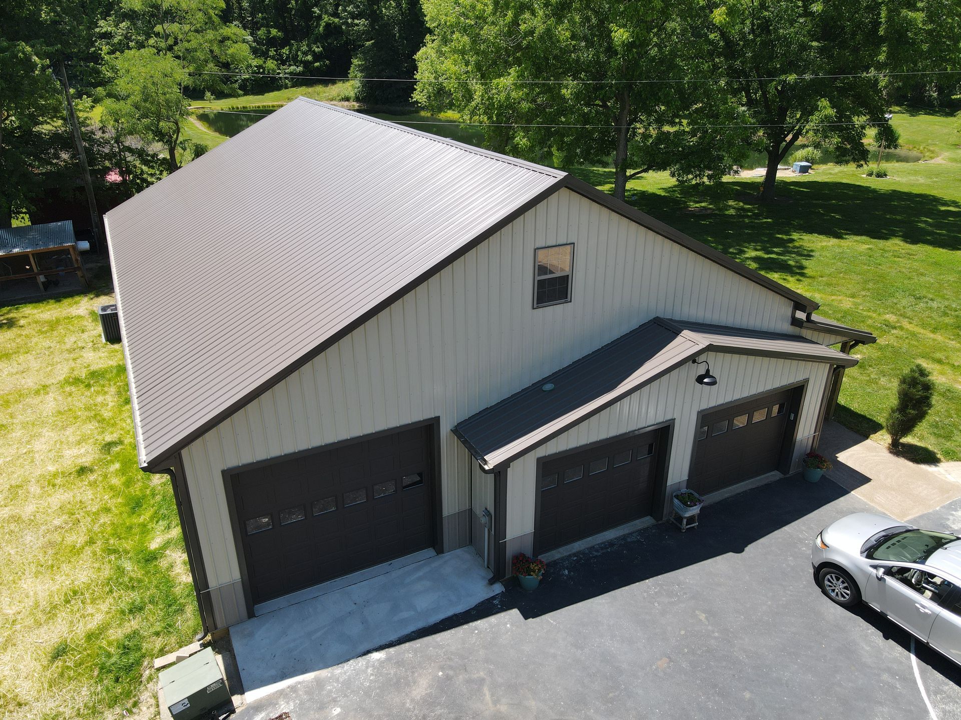 Aerial view of a gray two-car garage and driveway beside a house with a dark roof and green lawn