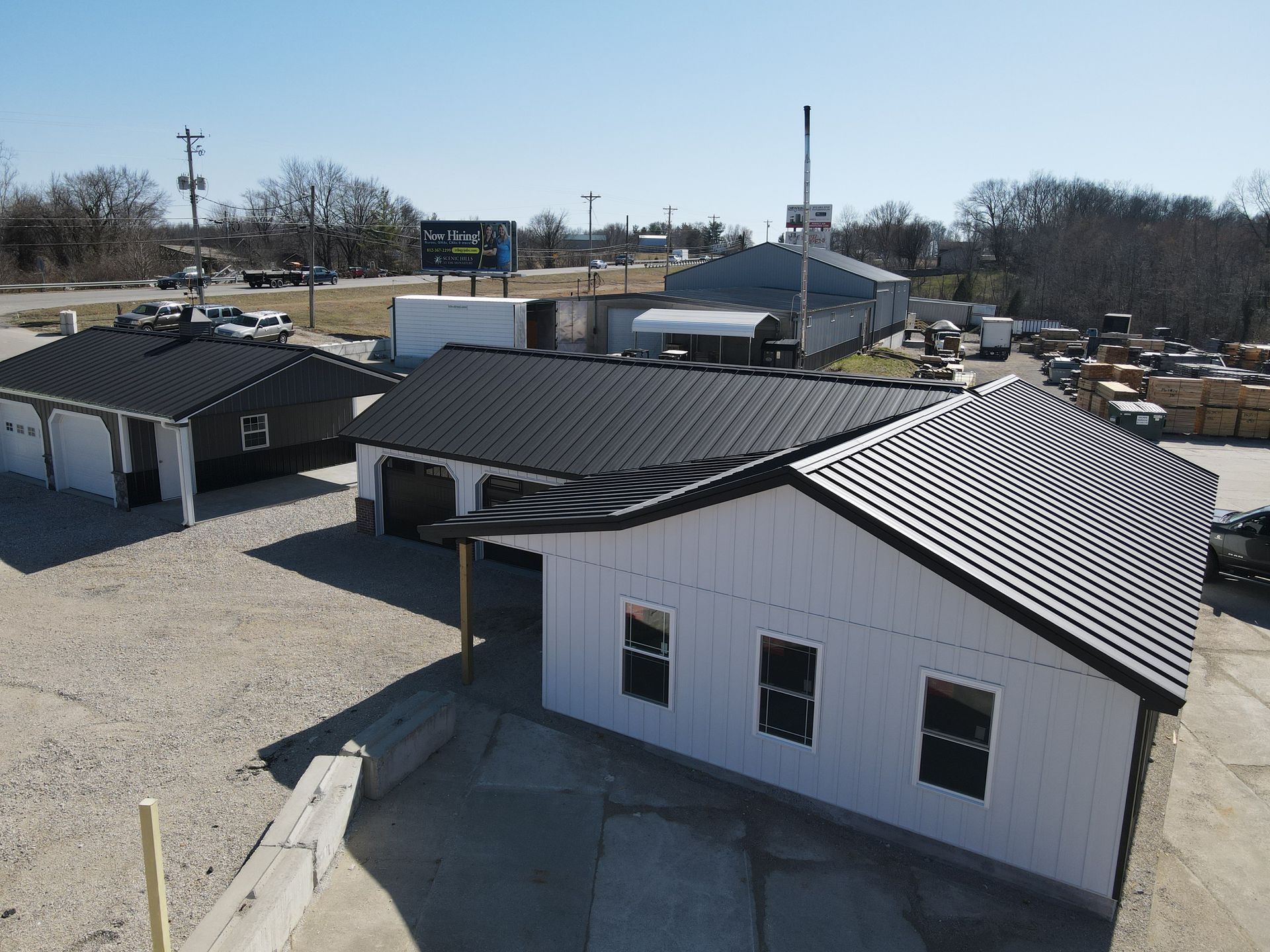 Row of small white and dark-roofed buildings in a gravel lot on a clear day