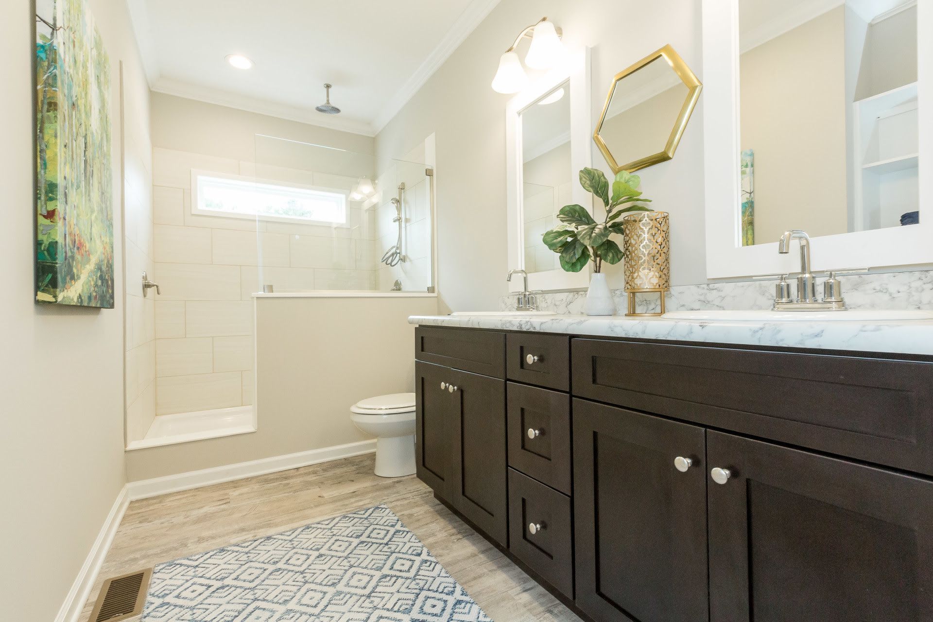 A kitchen stove and stainless steel range hood with a light-colored, rectangular tiled backsplash and white cabinets.