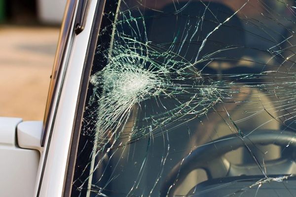 Cracked car windshield with a large impact spiderweb at the center