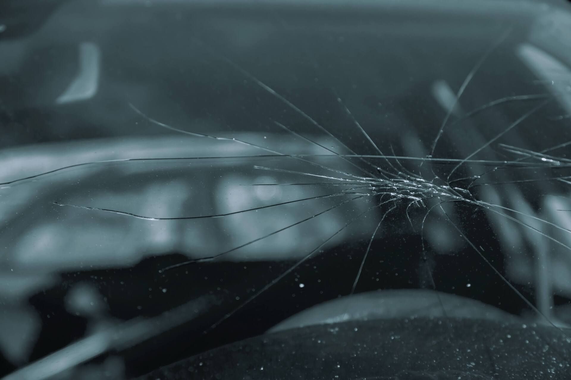 Cracked windshield of a car in the rain, with blurred interior visible