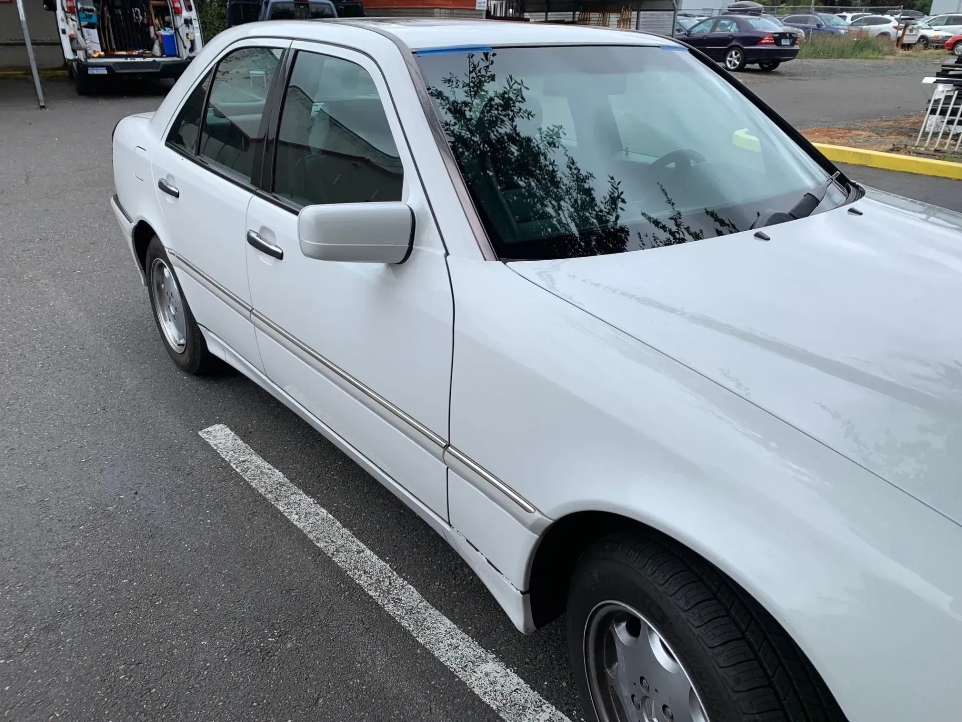 White Mercedes sedan parked on asphalt.