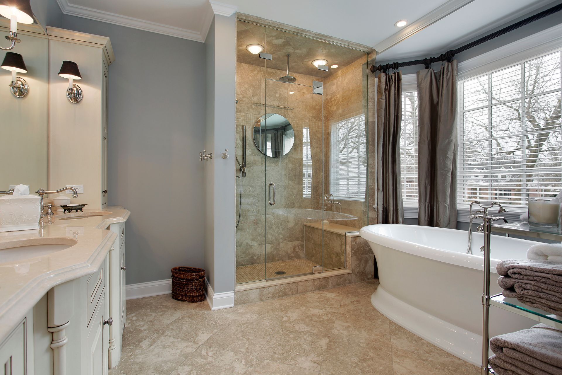 Bright bathroom with double vanity, glass shower, and freestanding tub by a window.