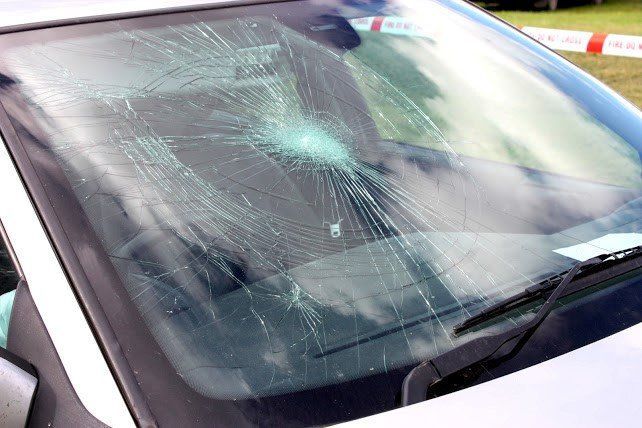 Cracked car windshield with extensive spiderweb damage across the glass