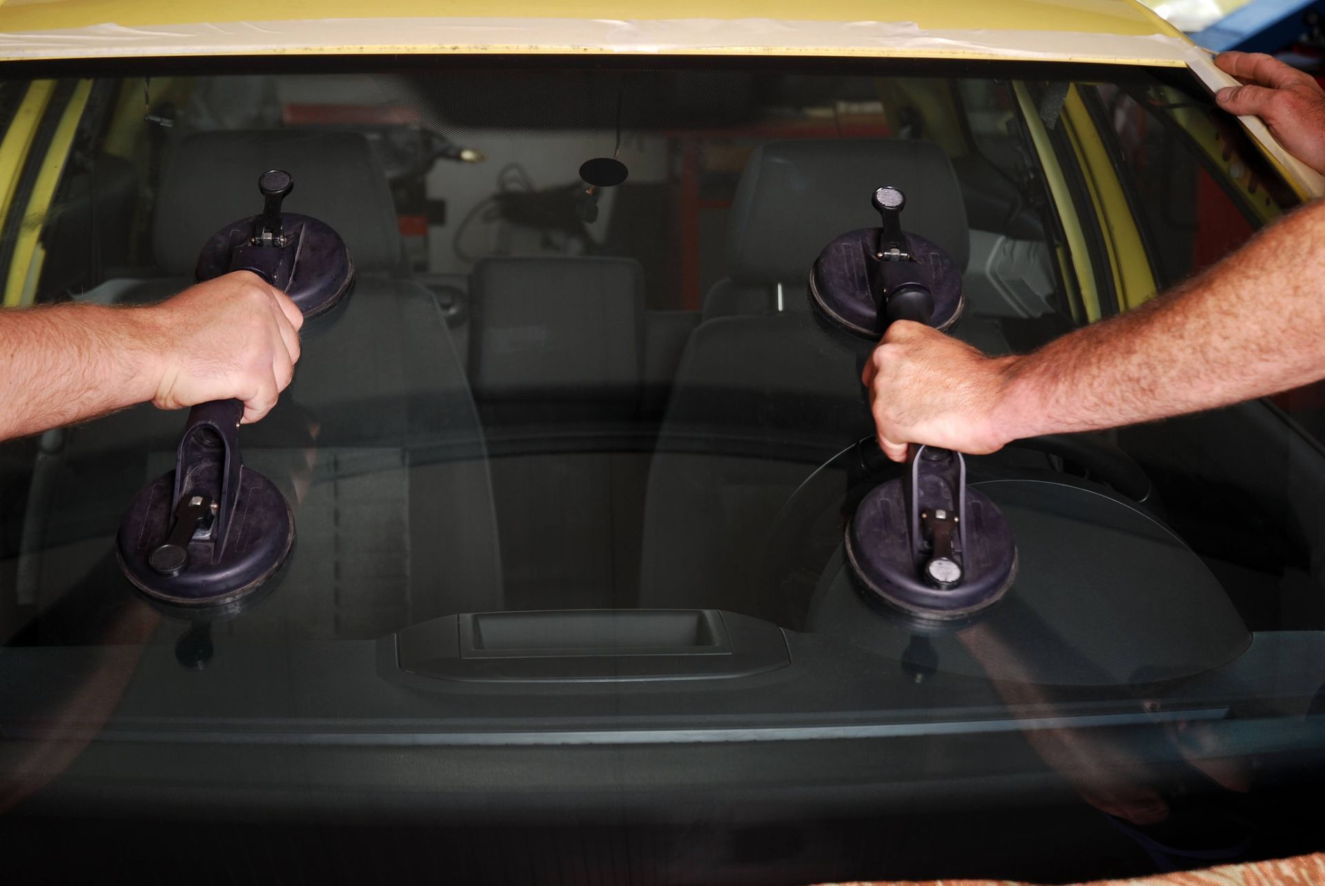 Hands using suction cups to repair a cracked car windshield