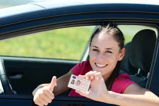 Woman smiling from a car window, holding up cash and giving a thumbs-up