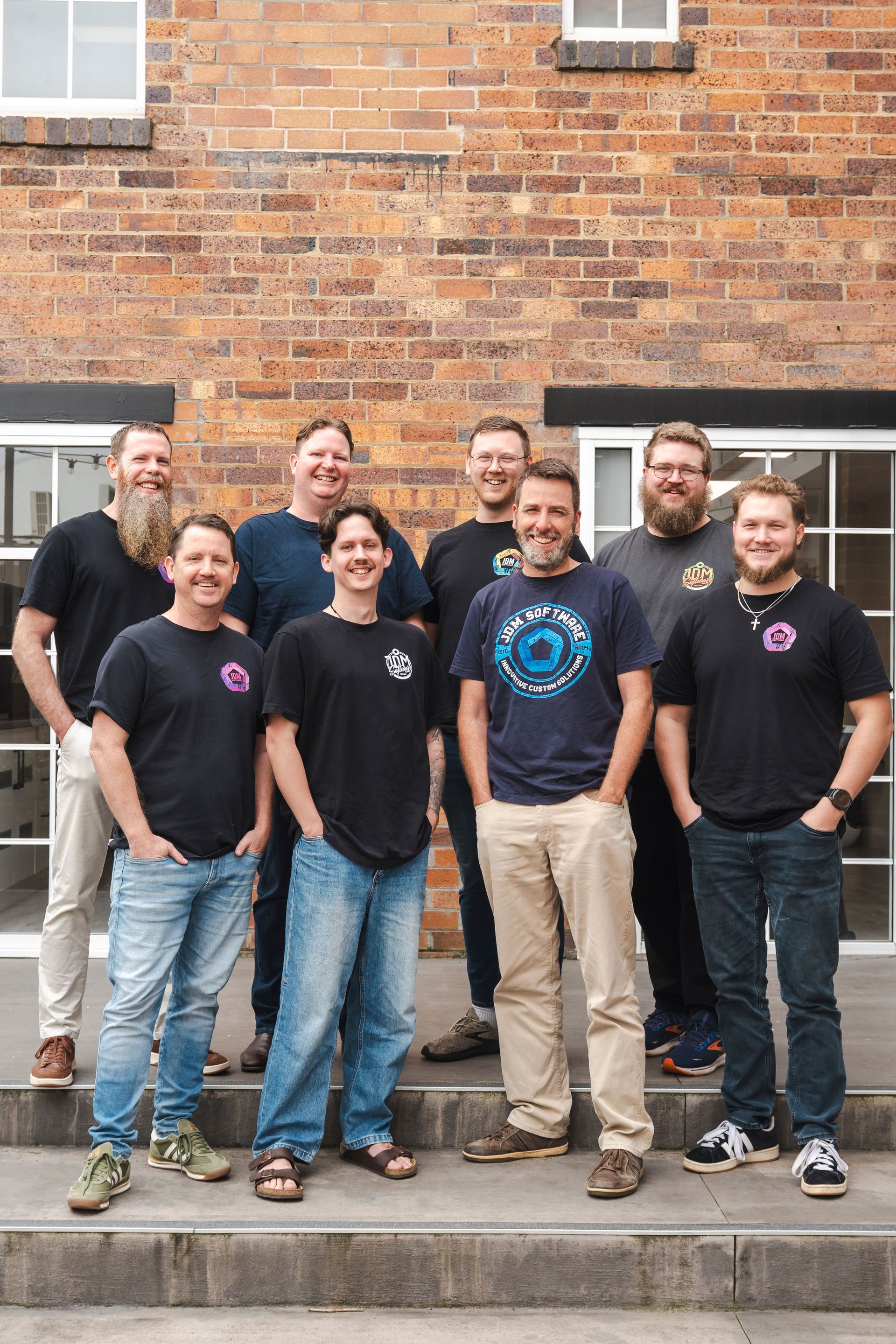 A group of men are posing for a picture in front of a brick building.