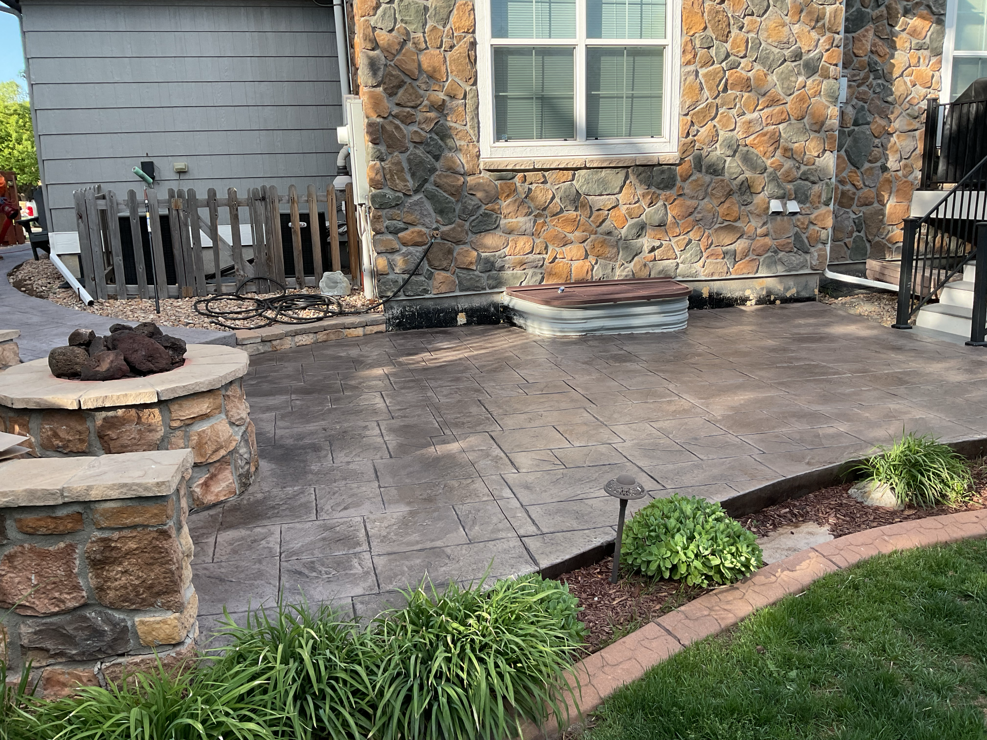 Stamped concrete patio with stone-veneer columns and a fire pit