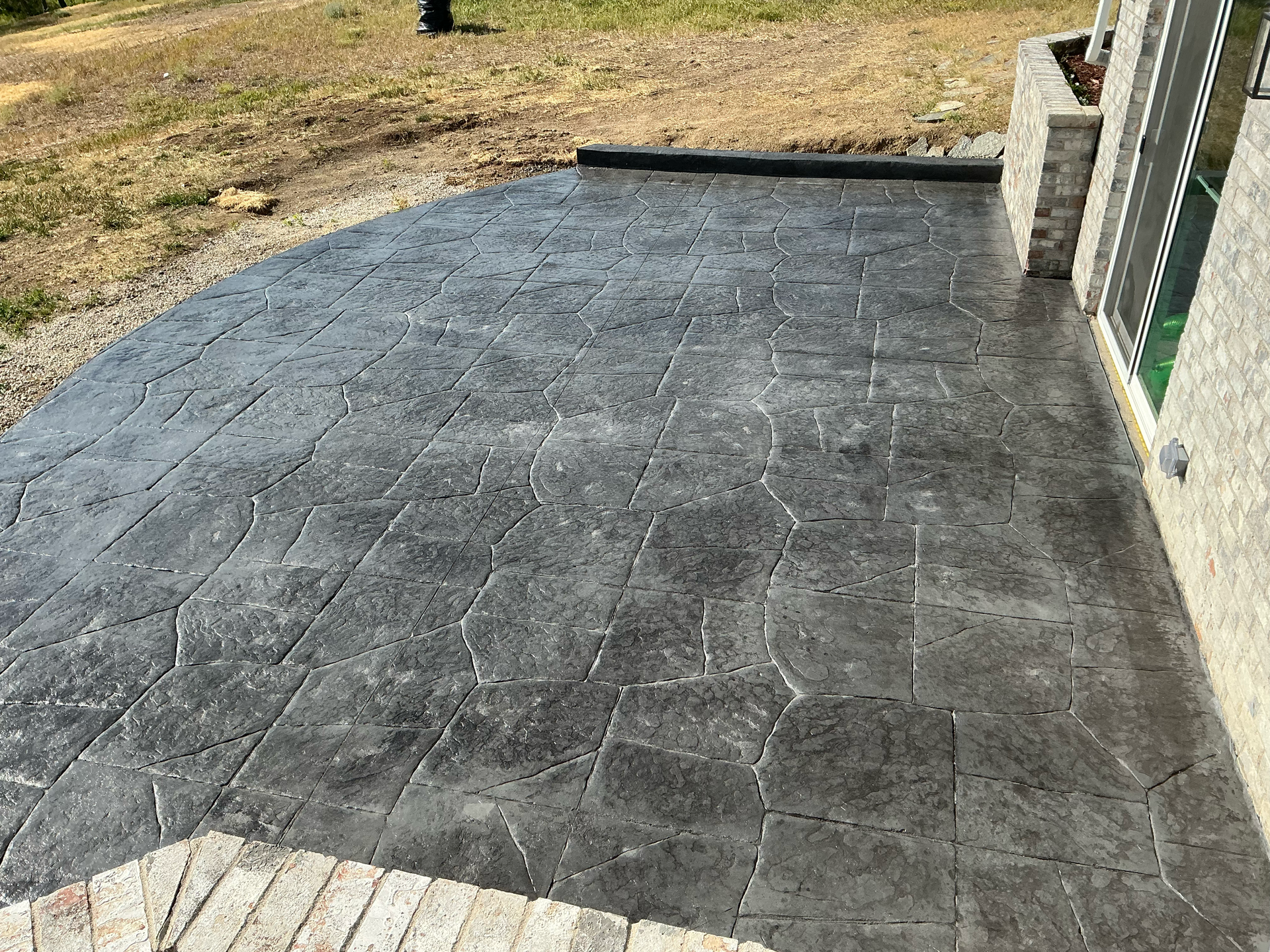 Stamped concrete patio in a flagstone pattern with a dark charcoal release color