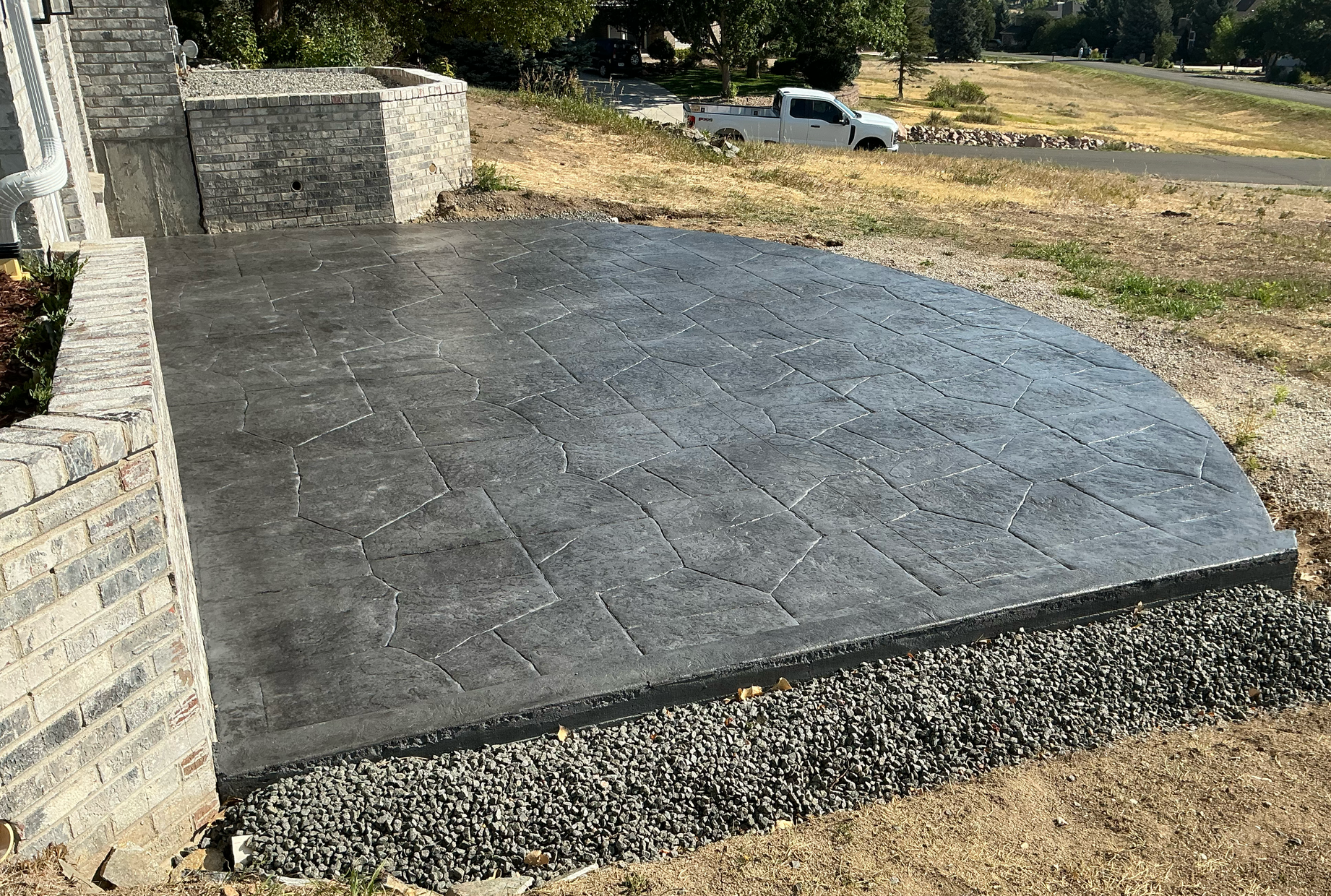 Curved stamped concrete patio in a flagstone pattern with a gravel border