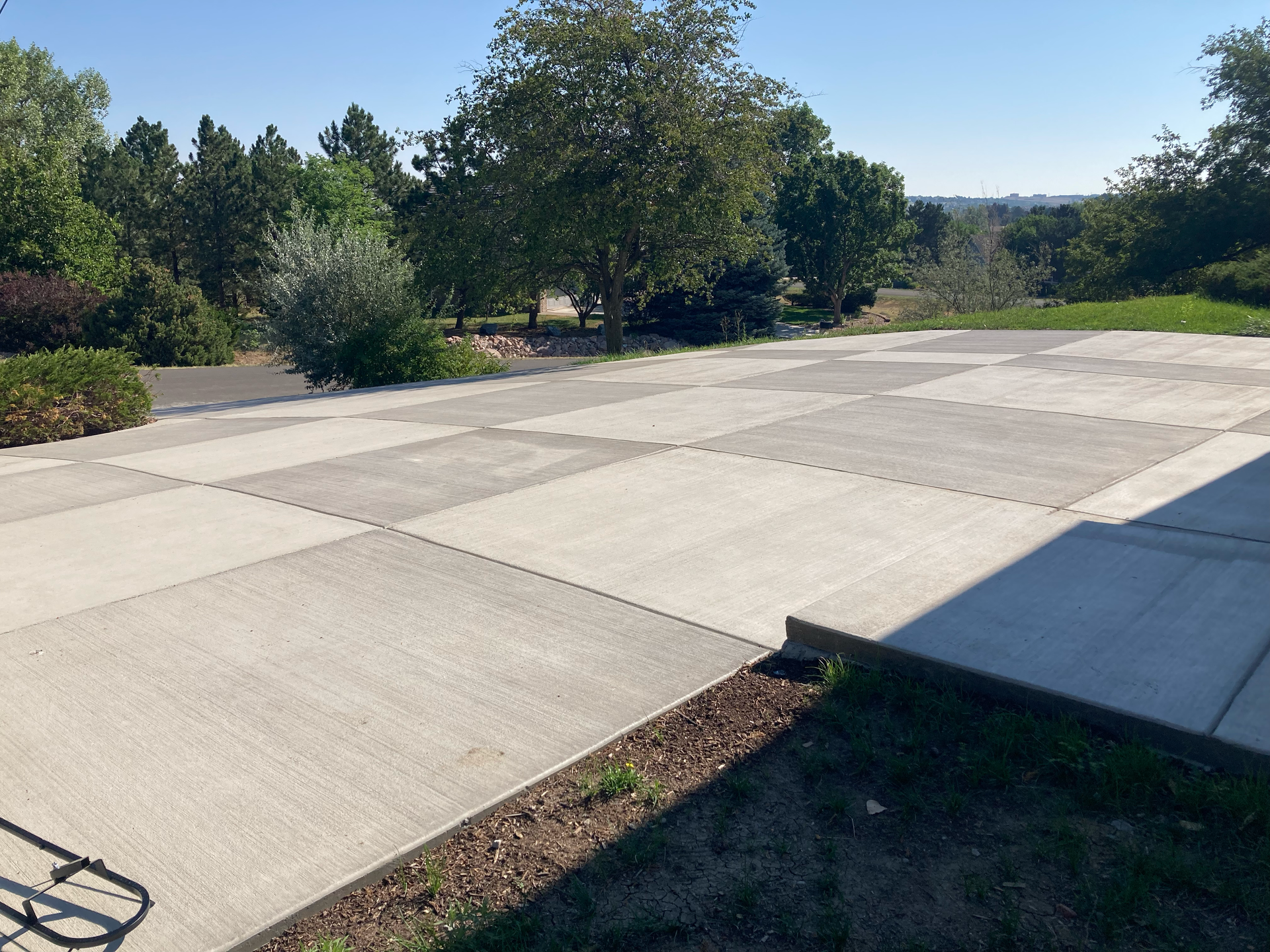 Wide finished concrete driveway with large scored panels leading toward the street