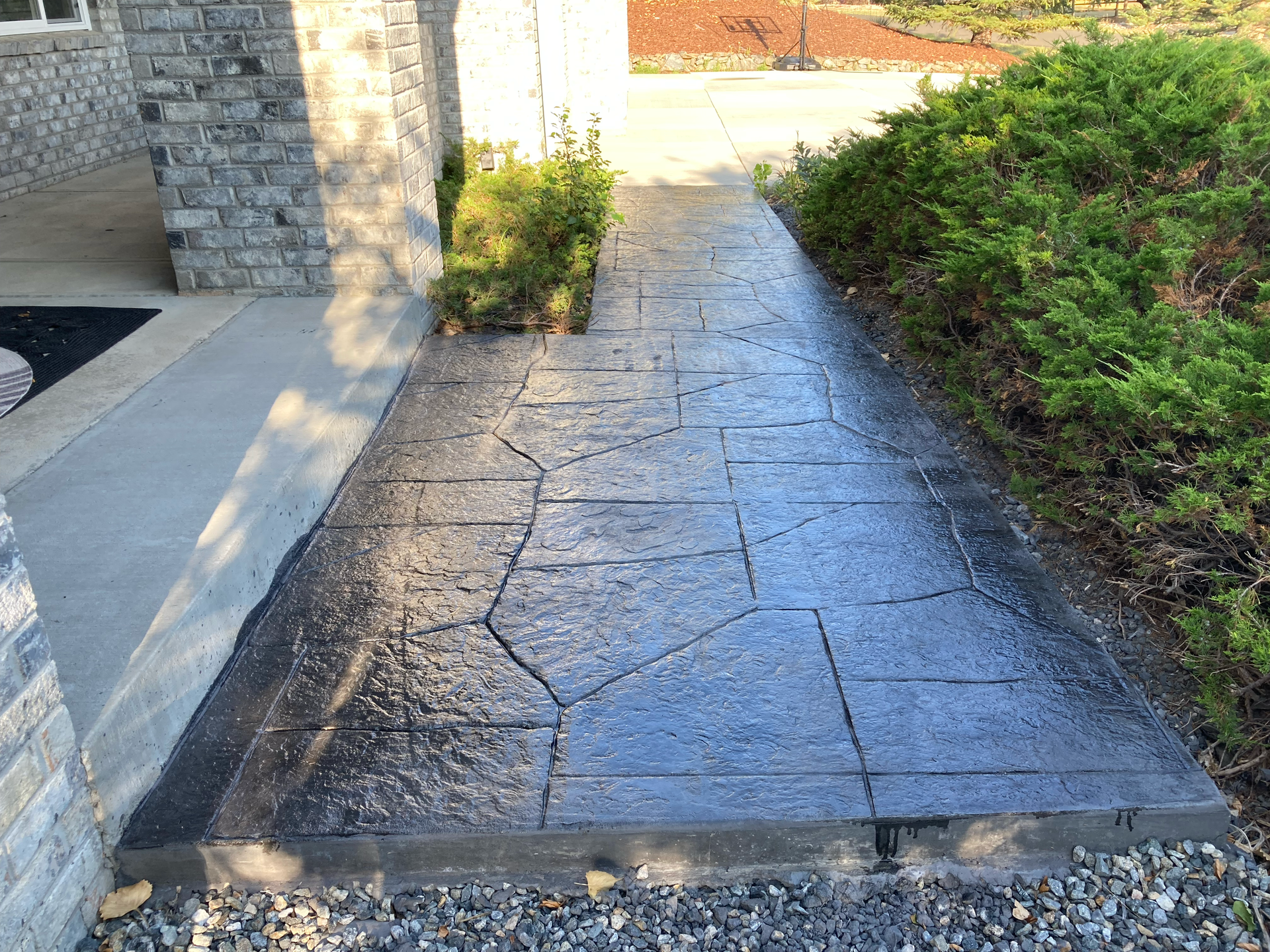 Long stamped concrete walkway in a flagstone pattern running alongside the house