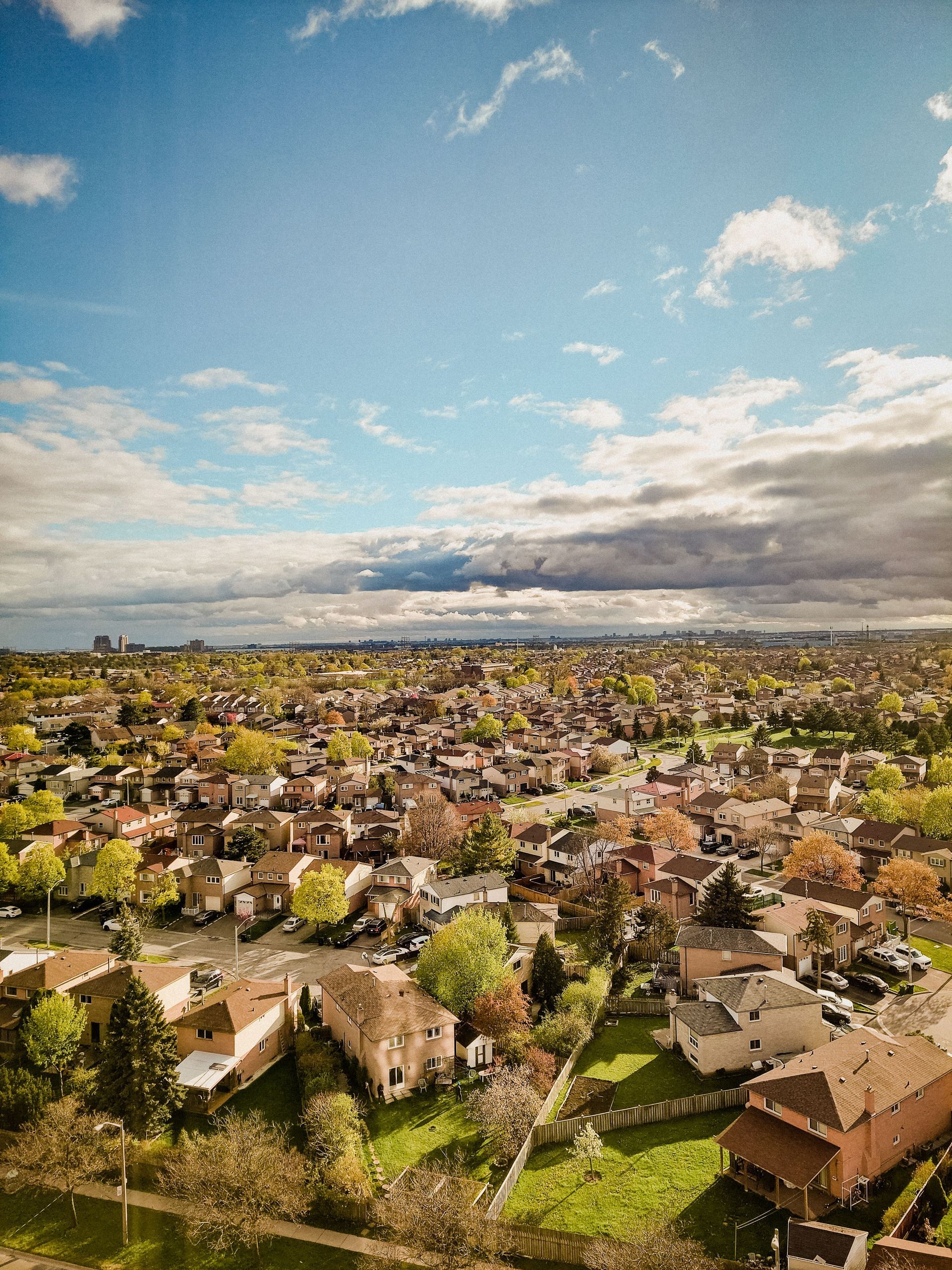 Aerial view of suburban neighborhood of single family homes with skyscrapers visible in the distance.