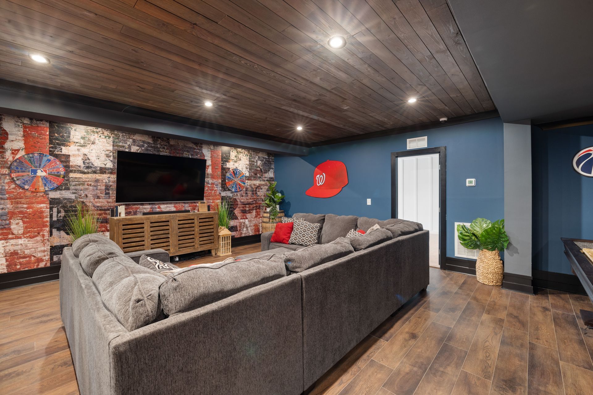 Basement turned into a man cave with a couch and a flat-screen TV on the wall. 