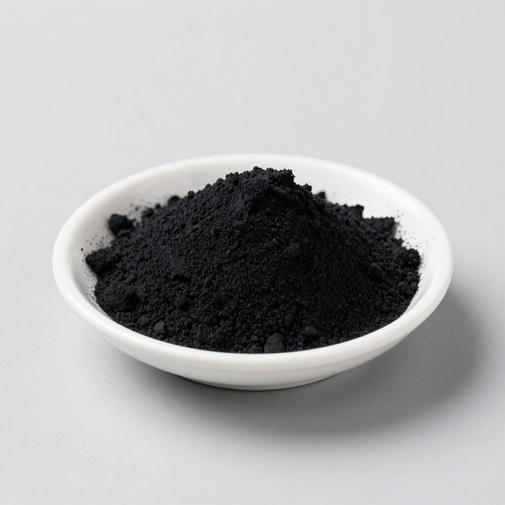 Polvo negro amontonado en un cuenco blanco sobre una superficie gris claro