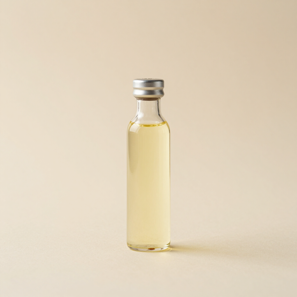 Pequeño vial de vidrio lleno de un líquido amarillo pálido sobre un fondo beige