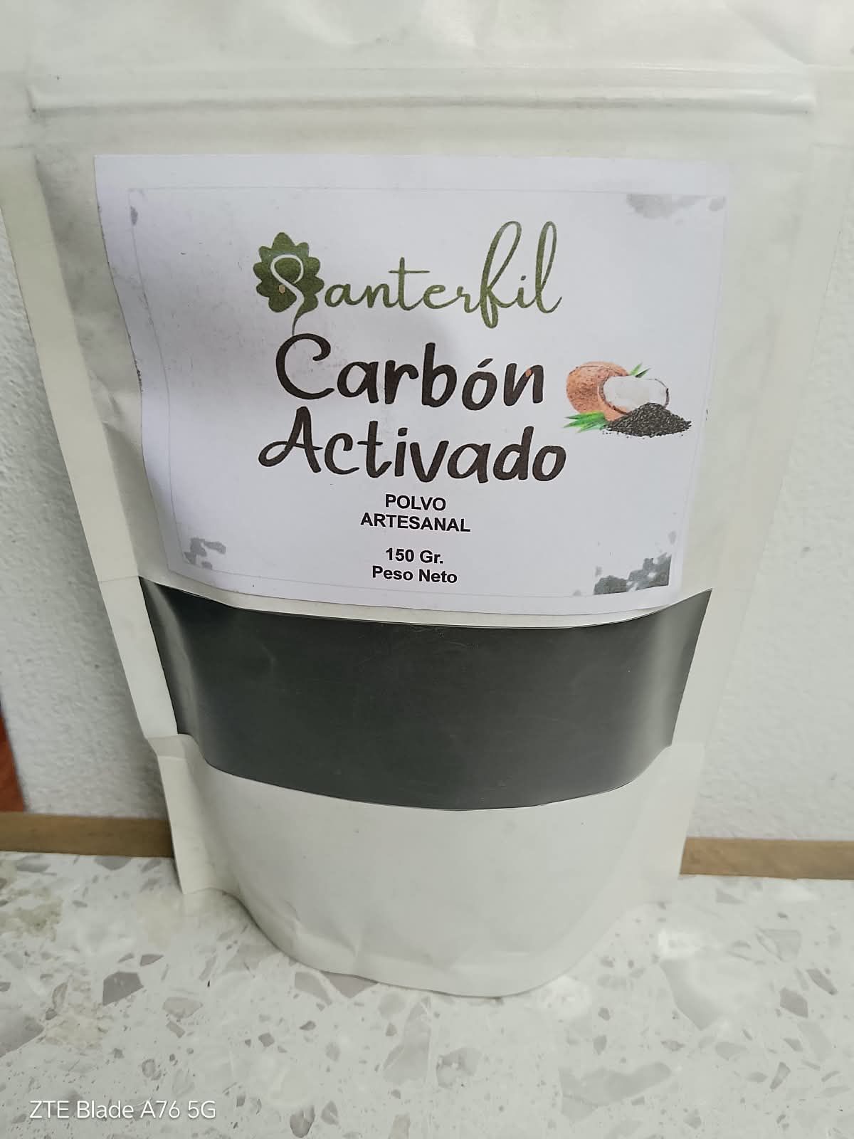 Bolsa de carbón activado con etiqueta verde y negra sobre una superficie blanca