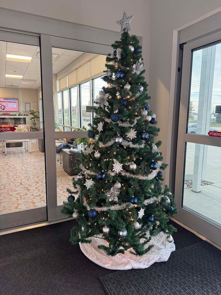 A christmas tree is sitting in a hallway next to a glass door.