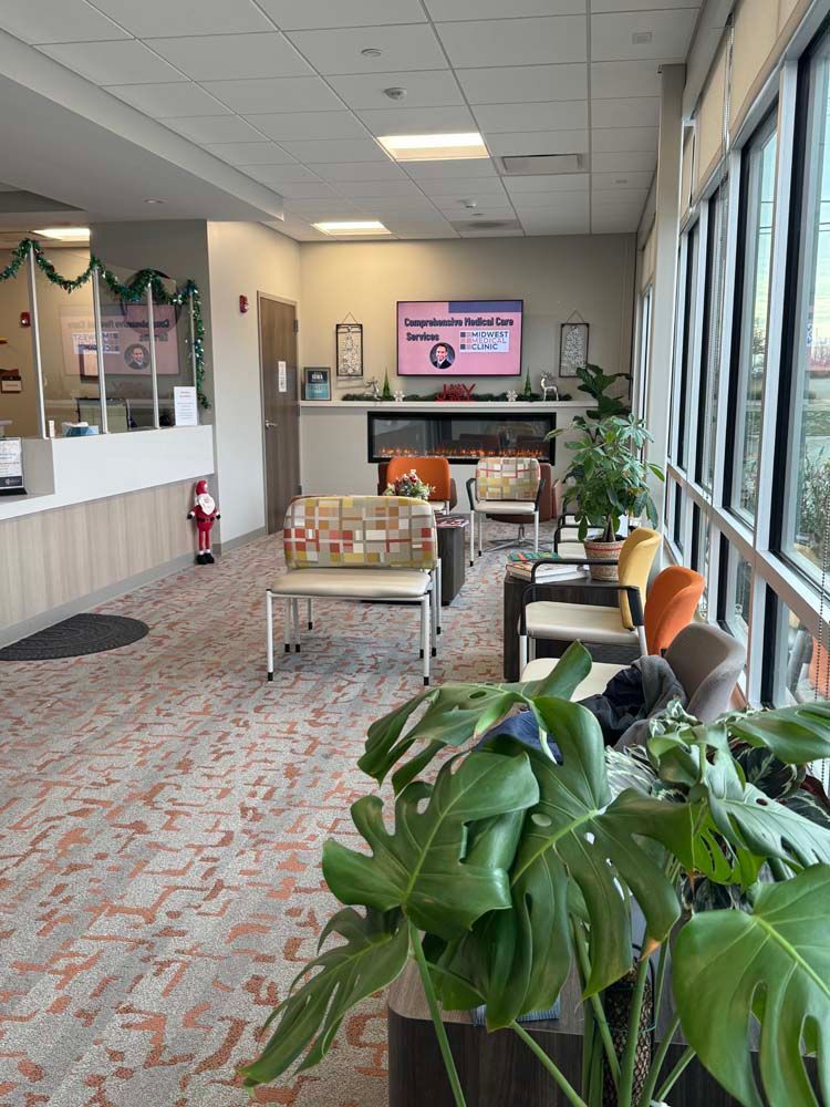 A waiting room in a hospital with a lot of chairs and plants.