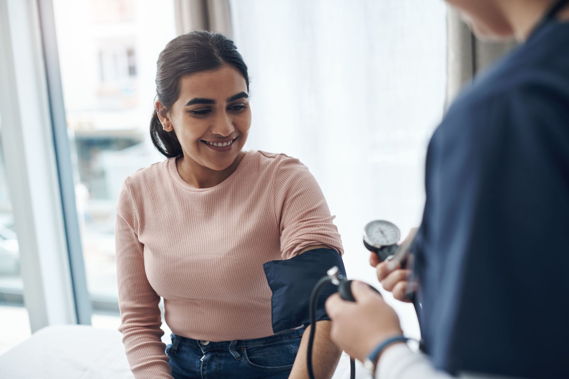 Person having blood pressure checked by a clinician in a bright medical office