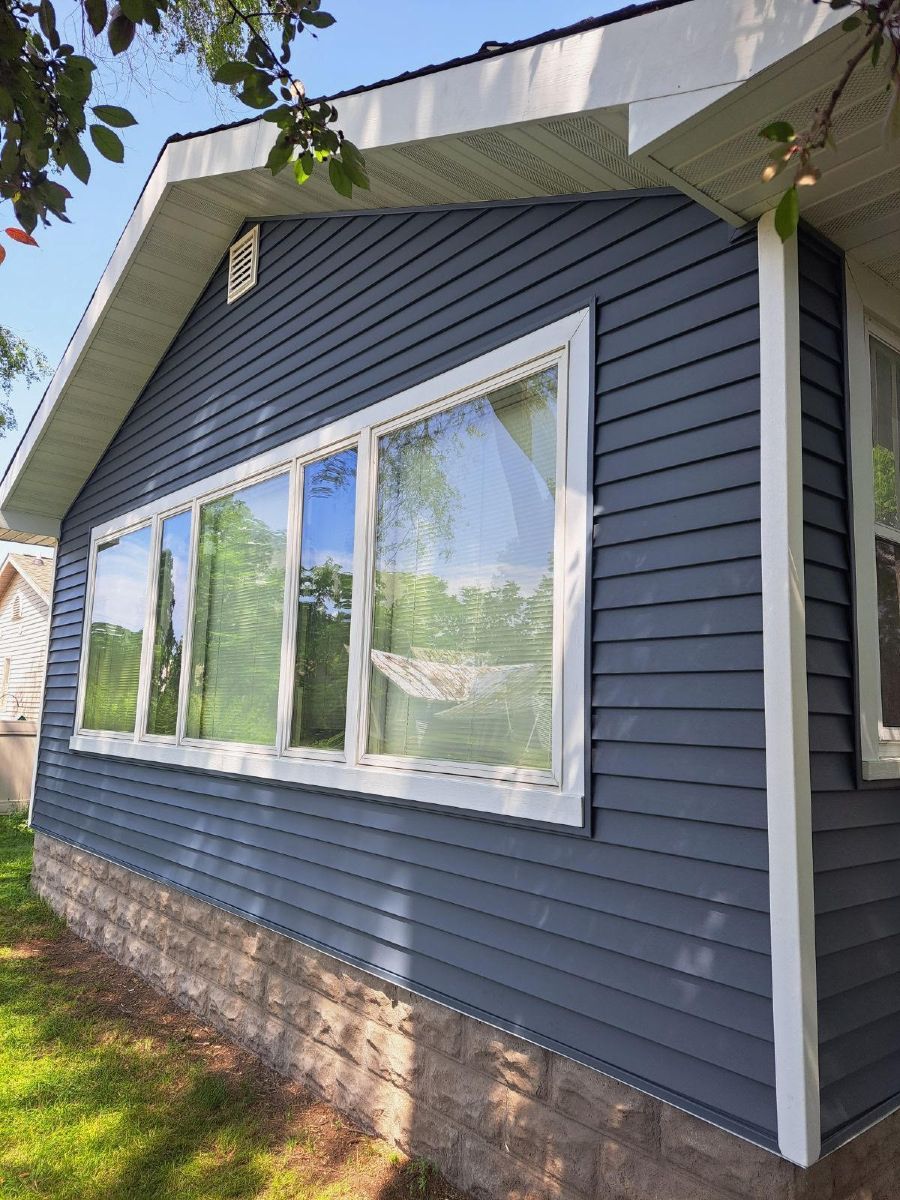 Blue-sided house exterior with large white-framed windows and a steep roofline