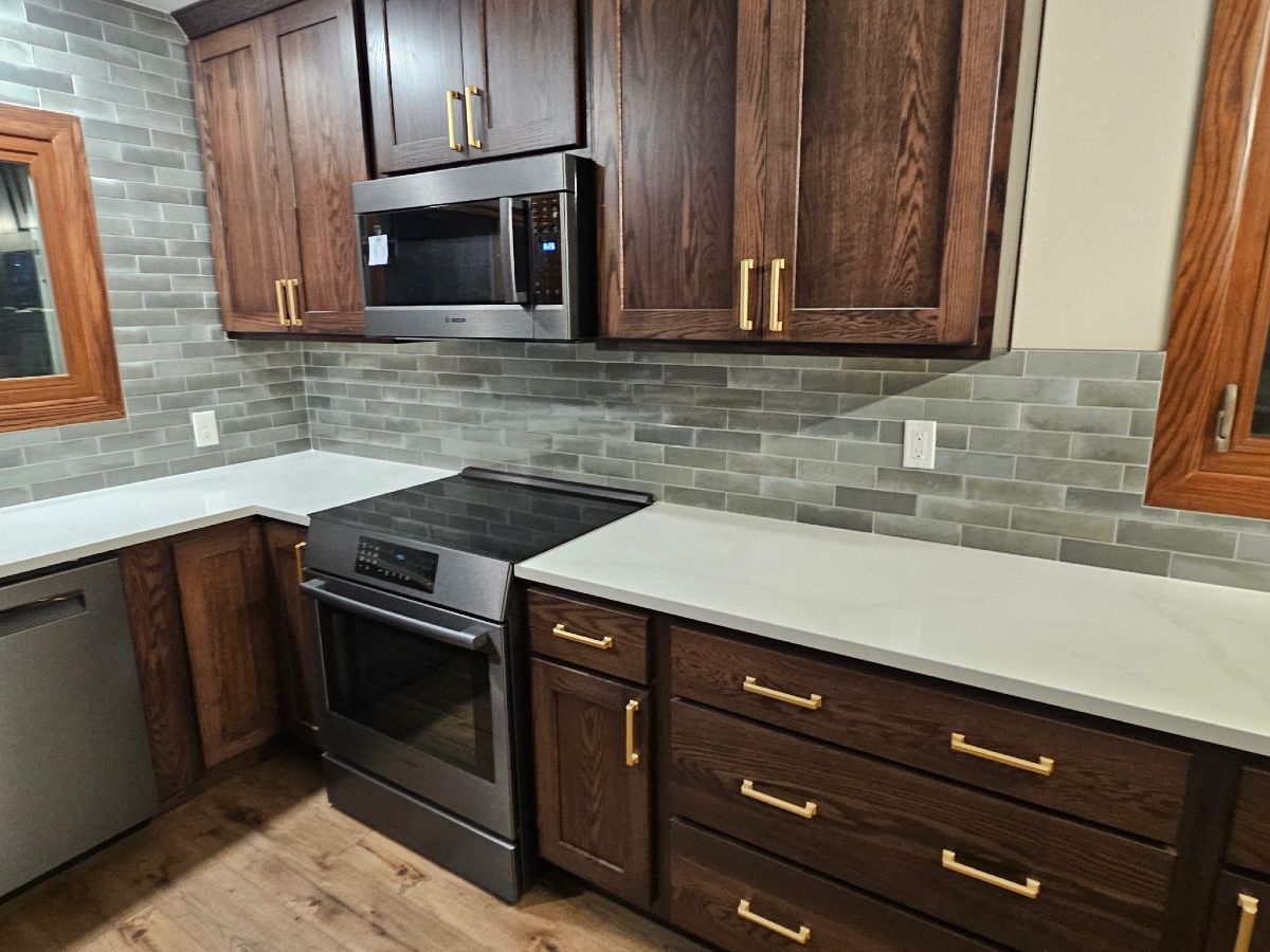 Modern kitchen with dark wood cabinets, stainless steel stove and microwave, and light countertops