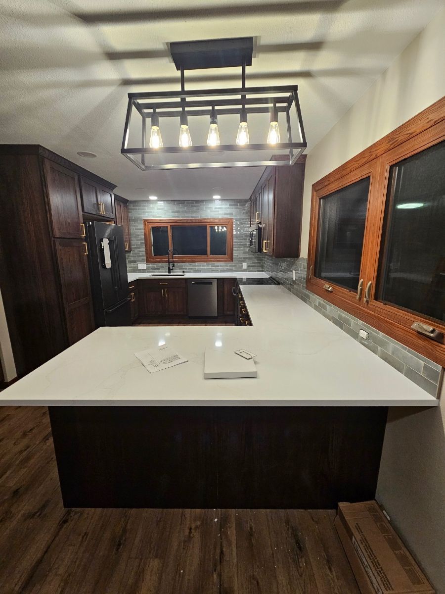 Modern kitchen with white island, dark wood cabinets, and hanging light fixture