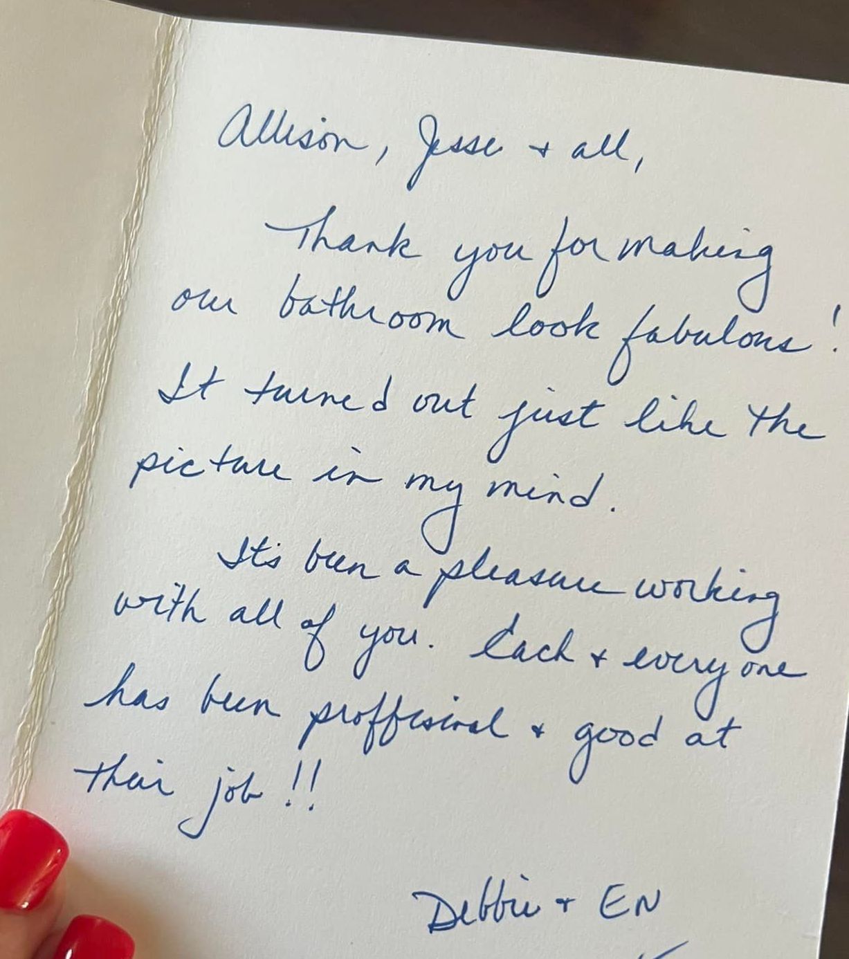Handwritten thank-you note on paper, with blue ink and a red-painted fingernail visible at the edge