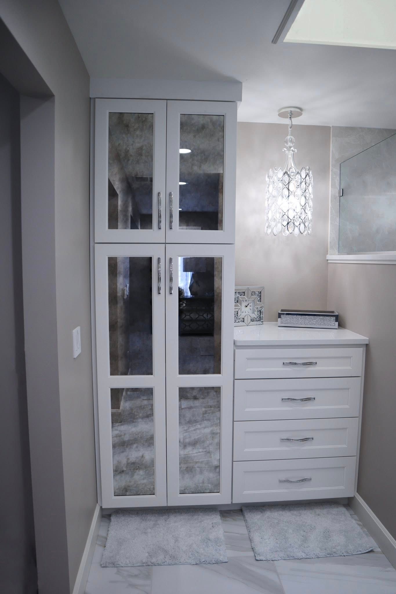 White hallway with mirrored closet doors, a white dresser, and hanging pendant light.