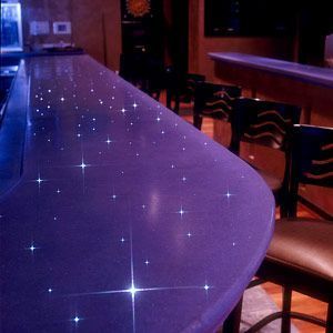 Sparkling purple bar counter in a dimly lit lounge with empty chairs.