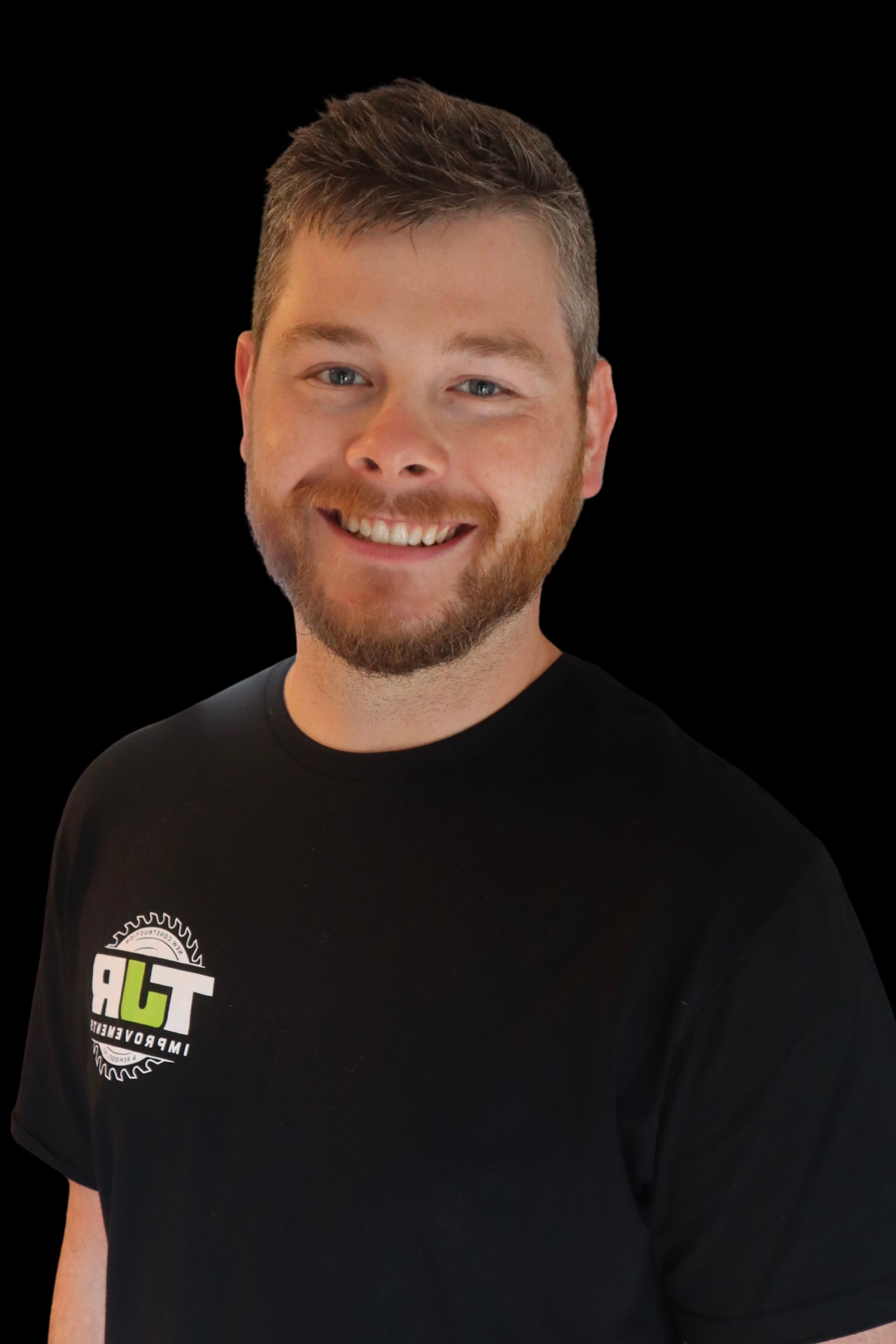 Smiling man in a black T-shirt with a logo on the chest, posed against a black background