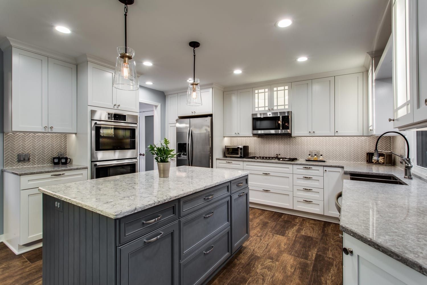 Bright modern kitchen with white cabinets, gray island, granite counters, and stainless steel appliances
