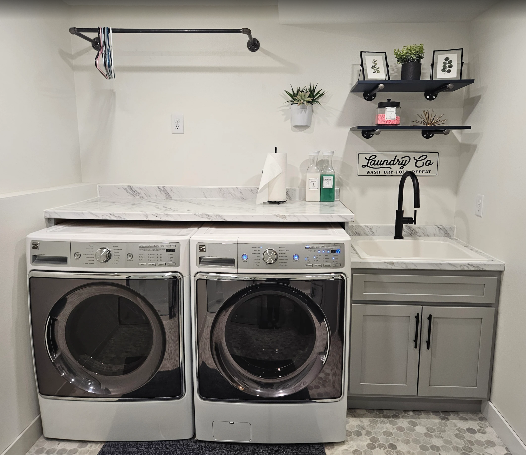 Laundry room with washer, dryer, utility sink, and wall shelves with decor