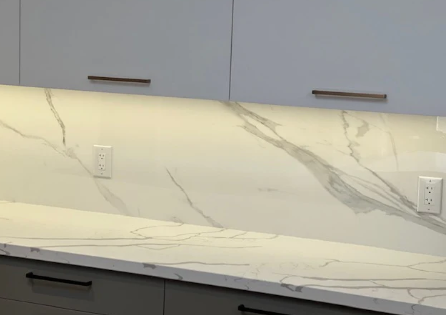 Modern kitchen backsplash with white marble-patterned backsplash and gray cabinets, under-cabinet lighting, and outlets