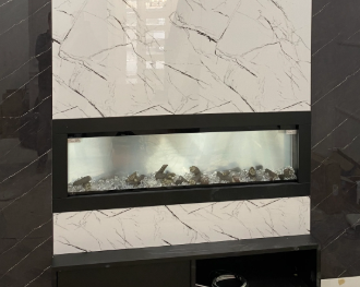 Modern linear fireplace set in a white marble wall with dark trim and decorative stones inside