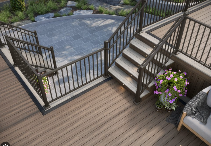 Backyard deck with black railings, stone patio steps, and potted flowers beside outdoor seating.