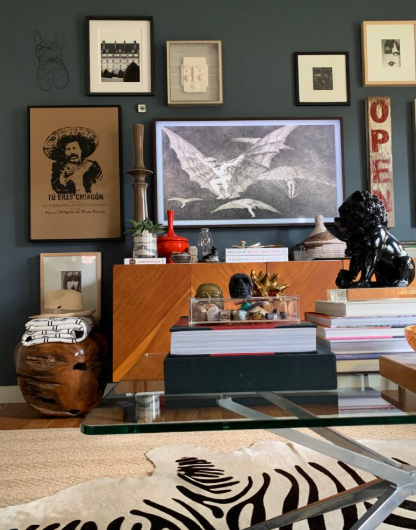 Cozy living room with framed art, books, a zebra-print rug, and a wood cabinet with decor.