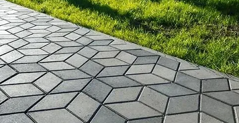 Gray geometric paved walkway beside green grass strip