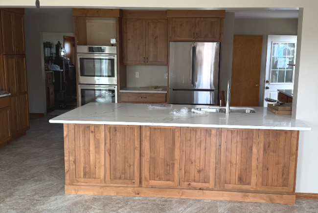 Modern kitchen with wooden cabinets, stainless steel appliances, and a large white island countertop