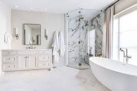Bright white modern bathroom with marble shower, double vanity, and freestanding bathtub
